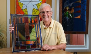 Bill Lagrange is surrounded by his works of stained glass