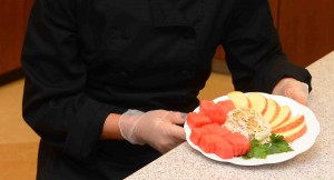 A Creamy Fruit Dip is plated with fresh cut watermelon and apples and ready to serve