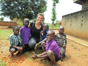 Kacey Klemesrud poses for a picture with a group of kids in Uganda