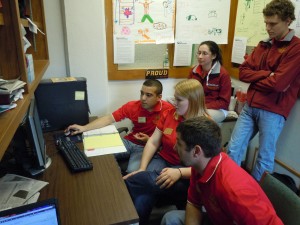 Five CALS ambassadors gather around a desk wearing matching polos