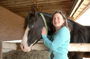 Alyssa Swan poses with her black, white faced horse at the ISU Horse Barn