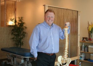 Anthony Davis holds a spinal cord model in his chiropractic clinic