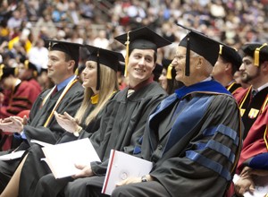 Graduates sit next to one another at commencement.
