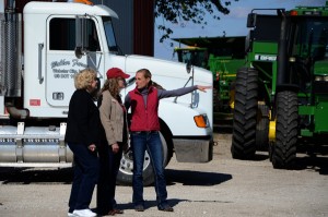 Farmers Patty and Kris Walker give ISU extension's Madeline Schultz a tour of their farm. Farm machinery can be seen in the background