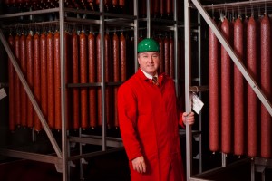 Dave McDonald wears a red lab coat and green hardhat while in the meat lab