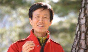 Headshot of Don Lee in windbreaker jacket with a forested background