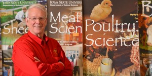 Maynard Hogberg poses in front of display signs for the ISU teaching farms