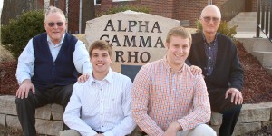 Alpha Gamma Rho fraternity members sit in front of the sign outside their house with their grandfathers who are alum of the fraternity