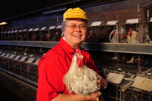 Sue Lamont holds chicken with caged chickens in the background