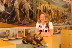 Laurie Hueneke Martens poses by a statue of a pig with a farming mural in the back.