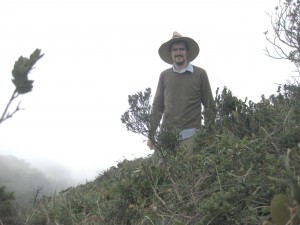Nate Looker walks through vegetation on a mountain in Guatemala City with fog in the background