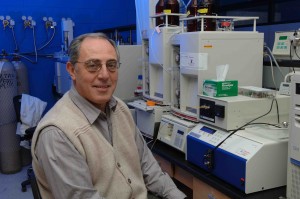 Biochemist Basil Nikolau sits by research machines in a lab