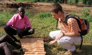 Sam Bird is taught by students at a Uganda school how to play the xylophone while on a Uganda Service Learning Trip.