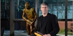 Professor Patrick Schnable sits holding a few ears of corn