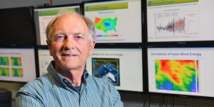 Headshot of Gene Takle with monitor screens of climate patterns in the background