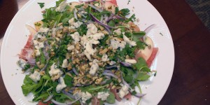 A plate is filled with salad and toppings including greens, onions, cheese, and nuts