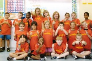 A Florida first grade class wear orange shirts saying "I am an Agronomist" while giving a thumbs-up sign