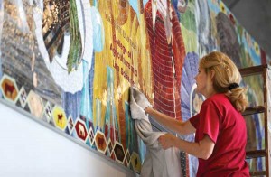 A woman cleans a mural in the Jeff and Deb Hansen Agriculture Student Learning Center that depicts the role of livestock in agriculture's sustainable cycle