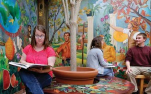 Students study in Horticulture Hall surrounded by murals