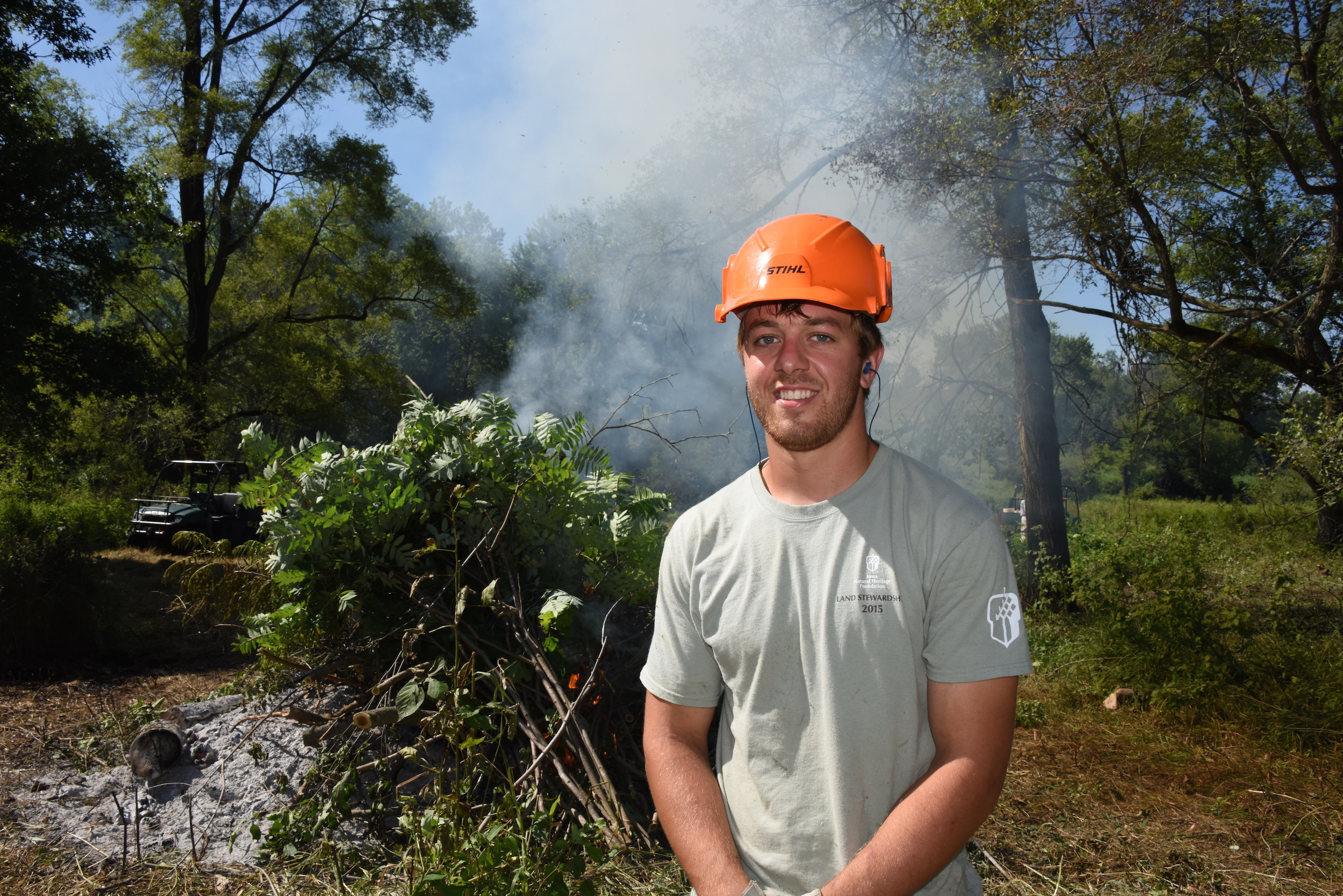 Matt Monahan stands in front of burning brush to help preserve the Iowa landscapes