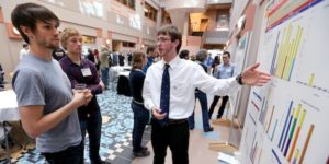 CALS student Ben Brown presents his poster at themposter session in the atrium of the Molecular Biology Building