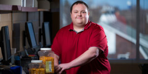 Grant Ives sits a computer desk with containers of corn kernels