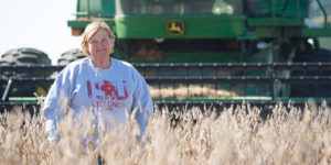 April Hemmes, an agricultural advocate, stands in front of John Deere combine in soybean field