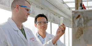Martin Gross, left, and Zhiyou Wen take a sample of algae in the portable algae water-treatment unit.