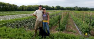 Karin Jokela and husband Dana are stand in front of the 14-acre organic vegetable farm that they own and operate.