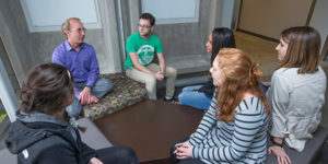 A professor and students sit and talk in Bessey Hall atrium
