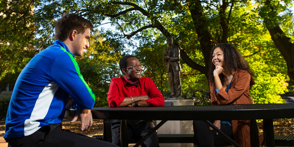 Professor Andrew Manu meets with students in Carver Courtyard in front of the statue of George Washington Carver