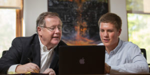 Dermot Hayes and Riley Arthur work together reviewing economic data on a laptop in 142 Curtiss.