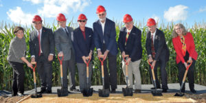 university administrators and donors wearing hardhats pose with shovels in a pile of grain