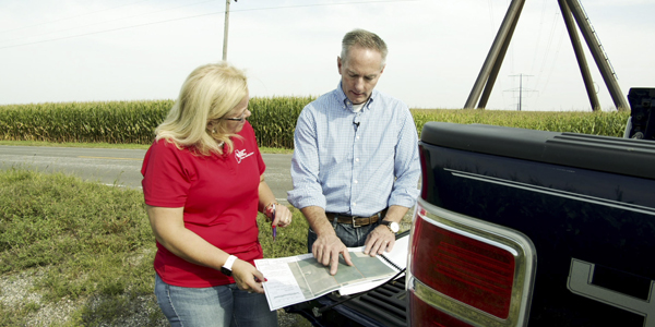 policy advocate reviews papers with a farmer on the bed of a pick up truck