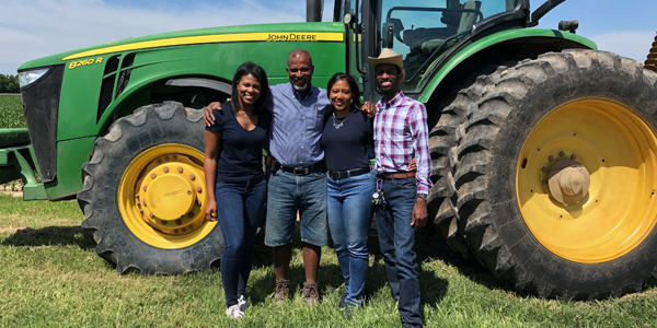 family poses in front of tractor