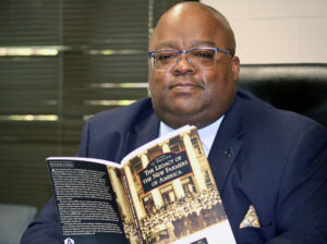 Antoine Alston, sitting holding a copy of "The Legacy of the New Farmers of America" book